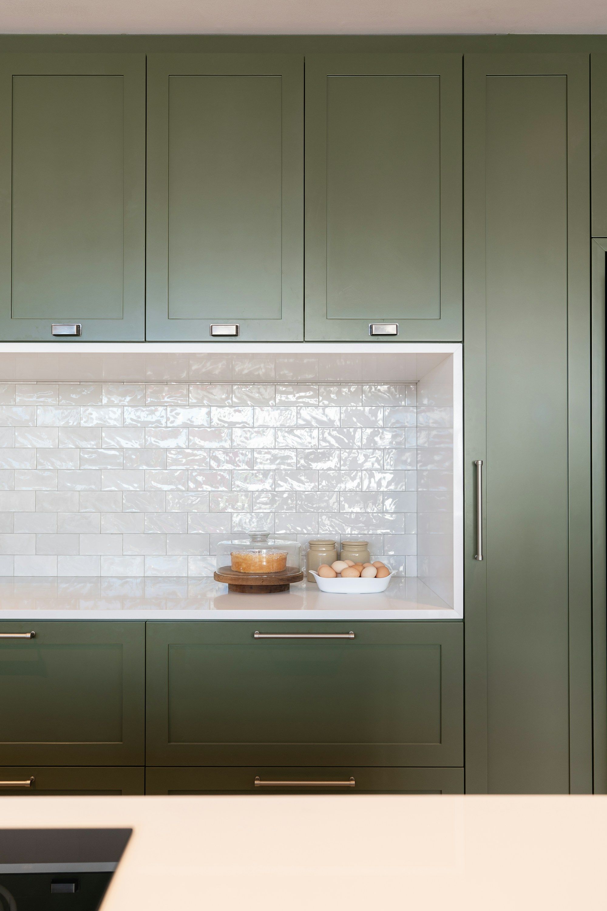 Muebles de cocina con frentes verdes mate y hornacina de azulejo blanco